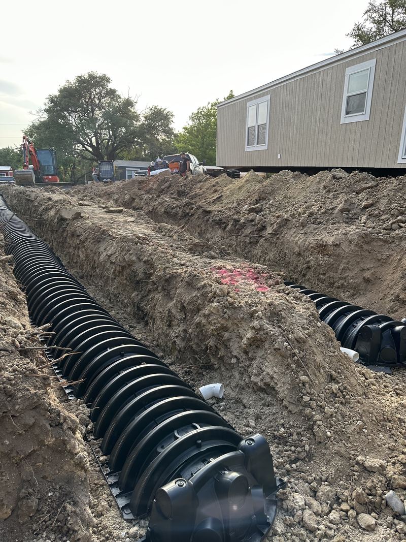 Drainfield trenches alongside a home being set